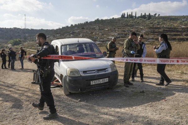 Israeli troops examine the car used by a Palestinian attacker at the scene of a shooting attack near the Israeli West Bank settlement of Kdumim, Thursday, July 6, 2023. The attacker opened fire, killing one Israeli, a day after Israeli forces withdrew from the largest military operation in the West Bank in two decades. The Israeli army said the attacker was shot and killed. (AP Photo/Mahmoud Illean)