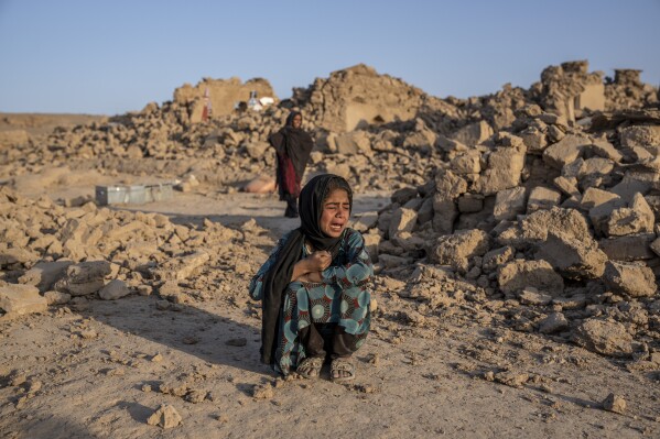 FILE- An Afghan girl cries in front of her house that was destroyed by the earthquake in Zenda Jan district in Herat province, western Afghanistan, on Oct. 11, 2023. Almost 100,000 children direly need support three months after earthquakes devastated western Afghanistan, the U.N. children’s agency said Monday, Jan. 15, 2024. (AP Photo/Ebrahim Noroozi, File)