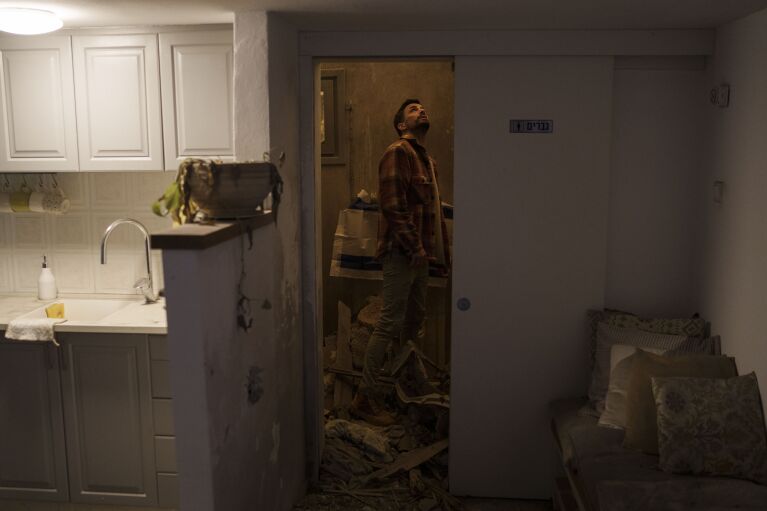 Nadav Tzabari looks at the damage inside his home in Kibbutz Nahal Oz, Israel, Wednesday, Feb. 7, 2024. (AP Photo/Leo Correa)