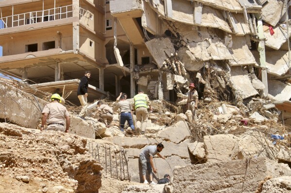 People look for survivors in Derna, Libya, Wednesday, Sept.13, 2023. Search teams are combing streets, wrecked buildings, and even the sea to look for bodies in Derna, where the collapse of two dams unleashed a massive flash flood that killed thousands of people. (AP Photo/Yousef Murad)