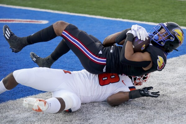 Kansas running back Torry Locklin, top, is tackled by Illinois linebacker Tarique Barnes (8) after scoring a touchdown during the first half of an NCAA college football game Friday, Sept. 8, 2023, in Lawrence, Kan. (AP Photo/Charlie Riedel)