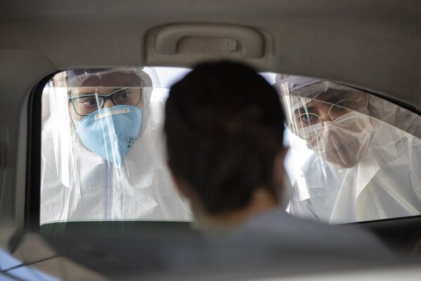 FILE - In this March 30, 2020, file photo, medical personnel check people inside their cars to find out if they have symptoms of COVID-19 in Guarulhos on the outskirts of Sao Paulo, Brazil. Sao Paulo is Brazil’s economic engine, most populous state, and also the epicenter of the outbreak. (AP Photo/Andre Penner)