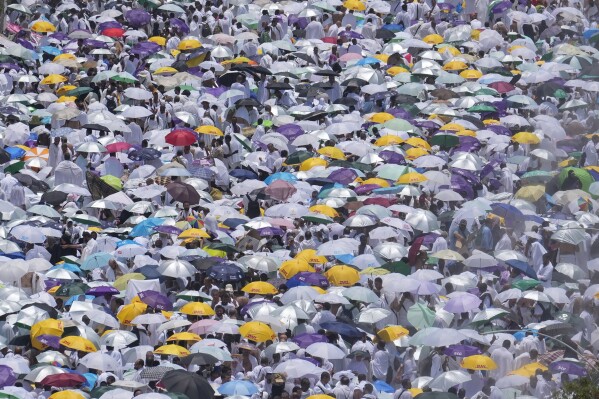 Muslim pilgrims use umbrellas to shield themselves from the sun as they gather outside Nimrah Mosque to offer the noon prayers in Arafat, on the second day of the annual hajj pilgrimage, near the holy city of Mecca, Saudi Arabia, Saturday, June 15, 2024. Masses of Muslims gathered at the sacred hill of Mount Arafat in Saudi Arabia for worship and reflection on the second day of the Hajj pilgrimage. (AP Photo/Rafiq Maqbool)