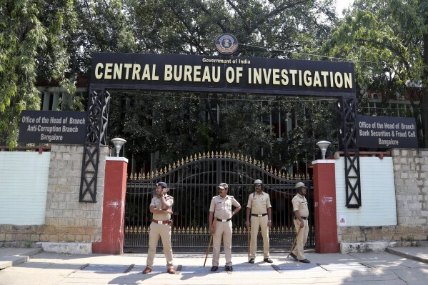 FILE- Police officials stand guard during a protest outside Central Bureau of Investigation (CBI) regional office in Bangalore, India, Oct. 26, 2018. India says several of its citizens have been duped to work with the Russian Army, a day after a federal investigation agency said it had busted a human trafficking network which lured young men to Russia. On Thursday, India’s Central Bureau of Investigation said at least 35 Indian nationals were sent to Russia through these agents. (AP Photo/Aijaz Rahi, File)