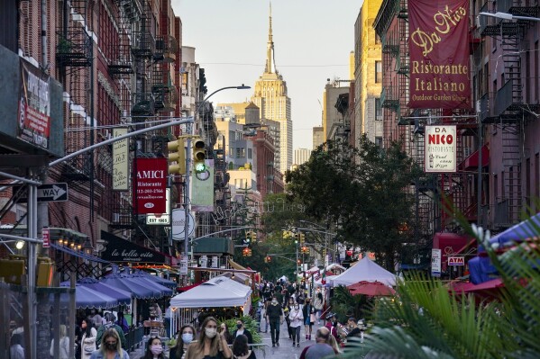 FILE - People walk through an area where restaurants operate outdoor spaces for dining that spread onto sidewalks and streets as part of continued COVID-19 economic impact mitigation efforts, Oct. 3, 2020, in New York. Americans didn’t let persistent inflation and lingering worries about a recession cut into summer spending on eating and drinking out. Retail sales at restaurants and bars surged from May through July 2023, compared with a year ago, despite prices remaining relatively elevated. (AP Photo/John Minchillo, File)