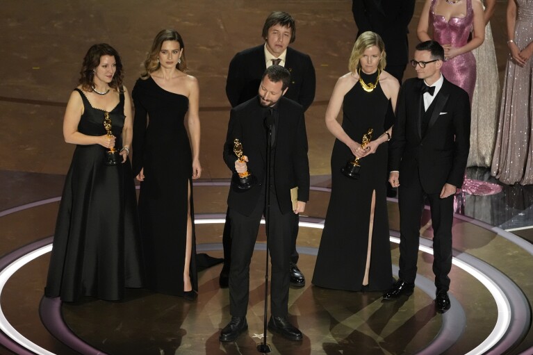 Raney Aronson-Rath, from left, Vasilisa Stepanenko, Mstyslav Chernov, Evgeniy Maloletka, Michelle Mizner, and Derl McCrudden accept the award for best documentary feature film for 