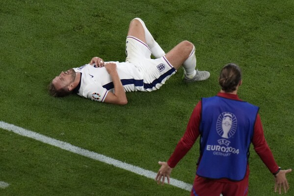 England's Harry Kane, left, grimaces in pain after a challenge by Serbia's Nikola Milenkovic during a Group C match between Serbia and England at the Euro 2024 soccer tournament in Gelsenkirchen, Germany, Sunday, June 16, 2024. (AP Photo/Alessandra Tarantino)