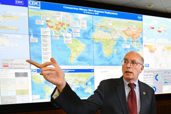 FILE - In this Feb. 13, 2020, file photo, Jay Butler, deputy director for infectious diseases at the Centers for Disease Control and Prevention (CDC), speaks to the media in regards to the novel coronavirus, while standing in front of a map marked with areas having reported cases, inside the Emergency Operations Center in Atlanta. In the United States, the nation with the most pandemic deaths, the reporting of vital coronavirus case and testing data is not keeping pace with its speedy spread. Public health officials nationwide lean too heavily on faxes, email and spreadsheets, sluggish and inefficient 20th-century tools. (AP Photo/John Amis, File)