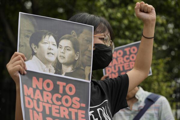A protester holds a photo bearing the photos of the late dictator's son, Ferdinand Marcos Jr., left, and Davao city Mayor Sara Duterte during a protest outside the Commission on Human Rights in Quezon city, Philippines on Sunday, Nov. 14, 2021. Philippine President Rodrigo Duterte's daughter, Sara, on Saturday registered her candidacy for vice president in next year's elections and was chosen as the running mate of the late dictator's son, in an alliance that has alarmed human rights activists. (AP Photo/Aaron Favila)