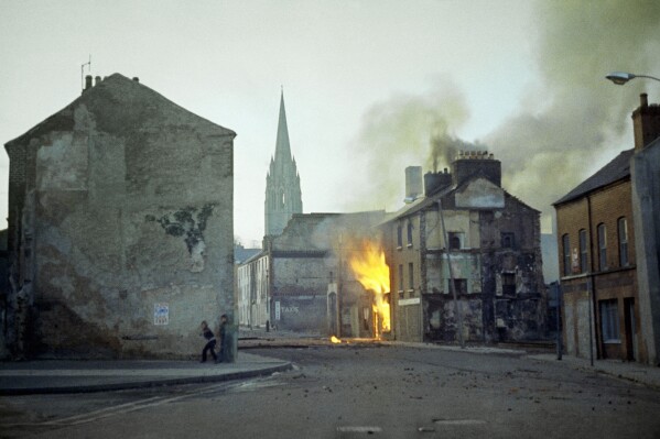 FILE - In this February 1972 file photo, a building burns in the bogside district of Londonderry, Northern Ireland, in the aftermath of Bloody Sunday, one of the the most notorious events of "The Troubles." Fifteen British soldiers who allegedly lied to an inquiry into Bloody Sunday, one of the deadliest days of the decades-long Northern Ireland conflict, will not face perjury charges, prosecutors said Friday. (AP Photo/Michel Laurent, File)