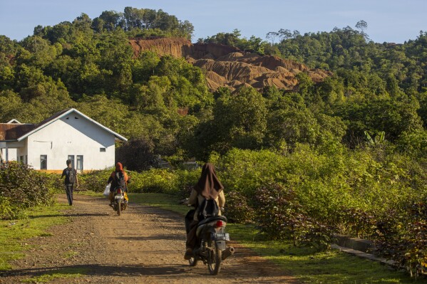 Students head to school as a hill that has been mined for nickel ore is visible in the background on Kabaena Island, Indonesia, Saturday, Nov. 16, 2024,. (AP Photo/Yusuf Wahil)