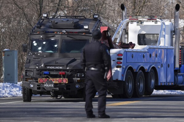 A police vehicle with what appears to be bullet pockmarks is towed near the scene where two police officers and a first responder were shot and killed Sunday, Feb. 18, 2024, in Burnsville, Minn. (AP Photo/Abbie Parr)