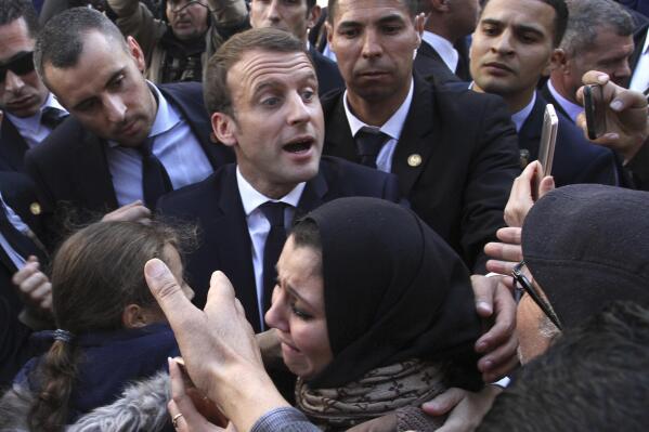 FILE- In this Dec.6, 2017 file photo, French President Emmanuel Macron meets residents in Algiers. Algeria has announced the immediate recall of its ambassador from Paris in a burst of fury over what it said were "inadmissible" comments attributed to French President Emmanuel Macron. (AP Photo/Anis Belghoul, File)