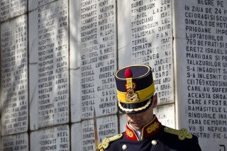 A honor guard soldier stands during a ceremony at a Jewish cemetery in Bucharest, Romania, Friday, Feb. 24, 2012, next to a monument bearing the names of Jews killed 70 years ago when the SS Struma, the ship they were on as refugees on the way to Palestine, was sunk by a Soviet torpedo in the Black Sea leading to the death of all but one of the 779 people on board. (AP Photo/Vadim Ghirda)
