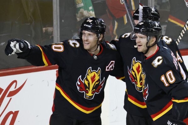 Calgary Flames' Blake Coleman, left, celebrates his goal against the Vegas Golden Knights with Jonathan Huberdeau during the third period of an NHL hockey game Thursday, March 14, 2024, in Calgary, Alberta. (Larry MacDougal/The Canadian Press via AP)