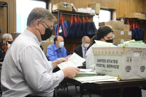 FILE - Election Bureau Director Albert L. Gricoski, left, opens provisional ballots alongside election bureau staff Christine Marmas, right, while poll watchers observe from behind at the Schuylkill County Election Bureau in Pottsville, Pa. on Tuesday, Nov. 10, 2020. A rural Pennsylvania county and its elected officials may have to pay the state’s elections agency hundreds of thousands of dollars to reimburse it for legal fees and litigation costs. .(Lindsey Shuey/Republican-Herald via AP, File)