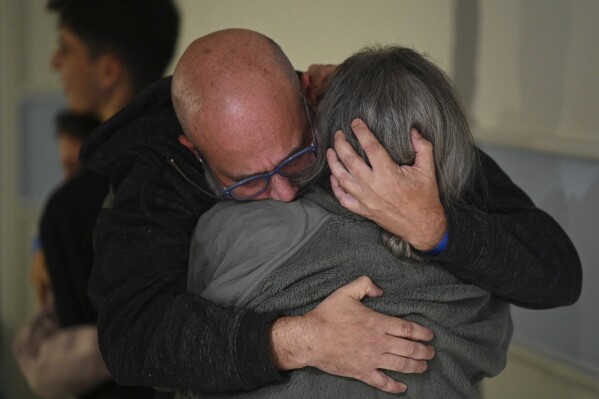 This handout photo provided by Haim Zach/GPO shows Sharon Hertzman, right, hugging her husband Hen Avigdori as they reunite at Sheba Medical Center in Ramat Gan, Israel, Saturday Nov. 25, 2023. Sharon Hertzman and her daughter Noam, 12 years old, not pictured, were released by Hamas after being held as hostages in Gaza for 50 days. (Haim Zach/GPO/Handout via AP)