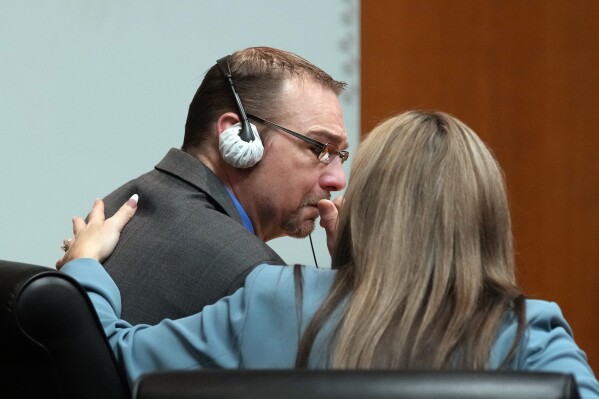 Defense attorney Mariell Lehman puts her arm on James Crumbley after he gets emotional after watching the video of his son walking through the halls of Oxford H.S. in a video shown in the Oakland County courtroom Friday, March 8, 2024, in Pontiac, Mich. Crumbley is on trial for involuntary manslaughter. He's accused of contributing to the tragedy at Oxford High School by failing to properly secure a gun used by son Ethan Crumbley. Four students were killed and more were wounded. (AP Photo/Carlos Osorio, Pool)