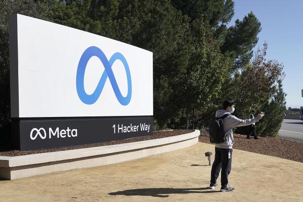 A Facebook employee take a selfie in front the company's new name and logo outside its headquarters in Menlo Park, Calif., Thursday, Oct. 28, 2021, after announcing that it is changing its name to Meta Platforms Inc. (AP Photo/Tony Avelar)