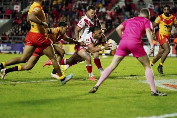 Tonga's Keaon Koloamatangi, centre, scores a try, during the Rugby League World Cup group D match between Tonga and Papua New Guinea at Totally Wicked Stadium, in St Helens, Merseyside, England, Tuesday, Oct. 18, 2022. (Martin Rickett/PA via AP)