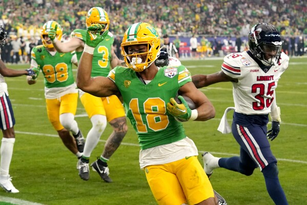 Oregon tight end Kenyon Sadiq, right, scores a touchdown during the first half on the NCAA Fiesta Bowl college football game, Monday, Jan. 1, 2024, in Glendale, Ariz. (AP Photo/Ross D. Franklin)