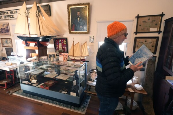 Jim Alfieri looks through his town's history book at the historical society for information about Pfc. Roland L. Bragg, Tuesday, Feb. 11, 2025, in Nobleboro, Maine. (AP Photo/Robert F. Bukaty)