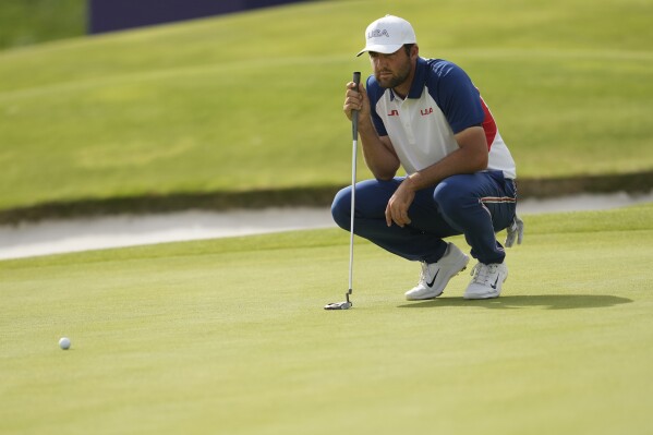 Scottie Scheffler, of the United States, looks at the lie of his putt on the 18th green during the final round of the men's golf at the 2024 Summer Olympics, Sunday, Aug. 4, 2024, at Le Golf National in Saint-Quentin-en-Yvelines, France. (AP Photo/Matt York)