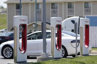 FILE - In this Monday, April 5, 2021 file photo, a Tesla electric vehicle charges at a station in Topeka, Kan. With strong sales of its electric cars and SUVs, Tesla on Monday, April 26, 2021 posted its seventh-straight profitable quarter. (AP Photo/Orlin Wagner)