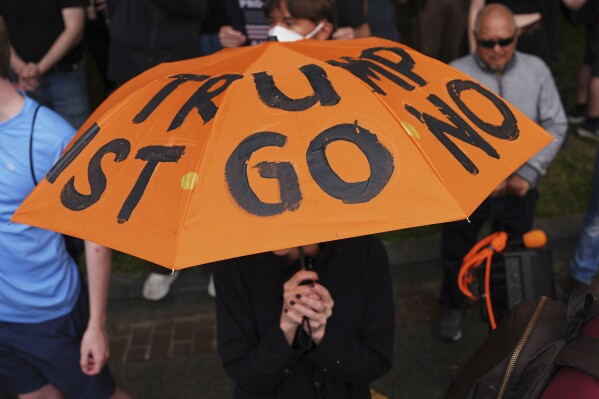 A demonstrators carries an umbrella with protest language on it during before a march taking place on the day of a military parade commemorating the Army's 250th anniversary, coinciding with President Donald Trump's 79th birthday, Saturday, June 14, 2025, in Washington. (AP Photo/Evan Vucci)