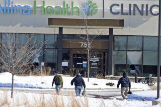 FILE - In this Tuesday, Feb. 9, 2021 file photo, law enforcement personnel walk toward the Allina Health clinic where multiple people were shot in Buffalo, Minn. Doctors say they're facing increasing threats of violence for refusing to prescribe opioids or trying to wean patients off the addictive painkillers. The issue was underscored by Tuesday's shooting at the Minnesota clinic.   (David Joles/Star Tribune via AP, File)