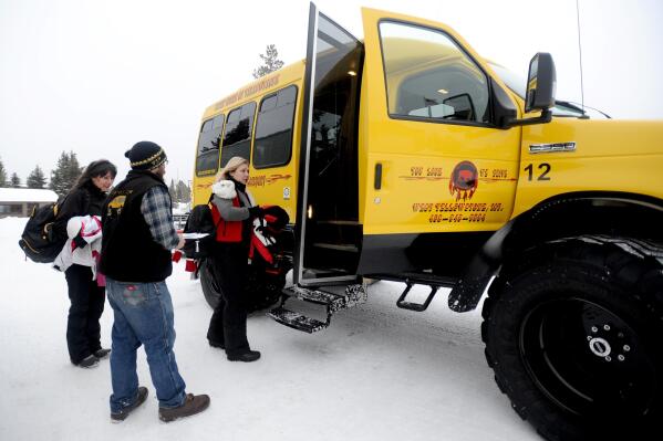 FILE - Tour Guide Ryan Edmiston ushers snowcoach passengers Deborah White and Monica Everett onto the coach Thursday, Jan. 15, 2016, at Yellowstone National Park. The park's winter season began Wednesday, Dec. 15, 2021. (Hannah Potes/The Billings Gazette via AP, File)