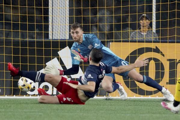 New England Revolution goalkeeper Matt Turner (30) makes a save as teammate Matt Polster slides past during the second half of a MLS soccer match against the Columbus Crew, Saturday, Sept. 18, 2021, in Foxborough, Mass. (AP Photo/Mary Schwalm)