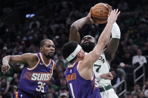 Boston Celtics guard Jaylen Brown (7) drives to the basket against Phoenix Suns guard Devin Booker (1) during the first half of an NBA basketball game, Thursday, March 14, 2024, in Boston. At left is Phoenix Suns forward Kevin Durant. (AP Photo/Charles Krupa)
