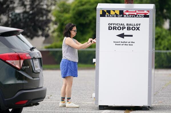 FILE - A woman drops a ballot into a drop box while casting her vote during Maryland's primary election, Tuesday, July 19, 2022, in Baltimore.  Whether a state requires voters to request an absentee ballot or participates in universal mail-in voting, all ballots cast by mail or dropped off at a drop box are vetted to ensure their legitimacy.(AP Photo/Julio Cortez, File)