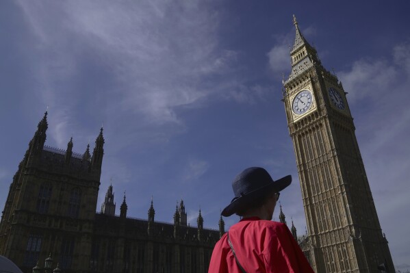 A woman walks past the Houses of Parliament in London, Monday, Sept. 11, 2023. Prime Minister Rishi Sunak has chastised China's premier for what he called unacceptable interference in British democracy after a newspaper reported that a researcher in Parliament was arrested earlier this year on suspicion of spying for Beijing. (AP Photo/Kin Cheung)