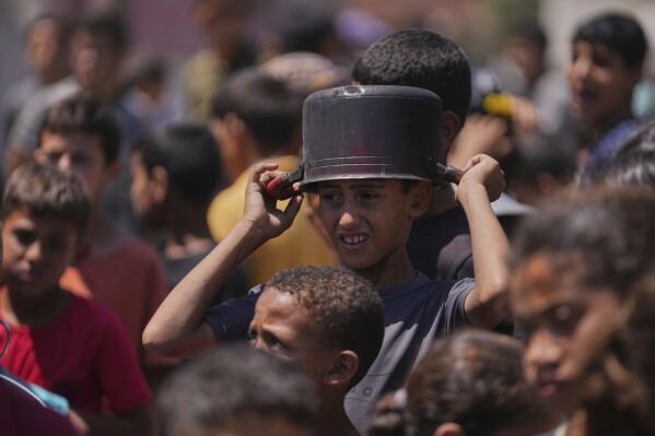 Young Palestinians are waiting to collect donated food at the Food Distribution Kitchen in Deir Albara, Gaza Strip on Friday, May 30, 2025 (AP Photo/Abdel Kareem Hana)