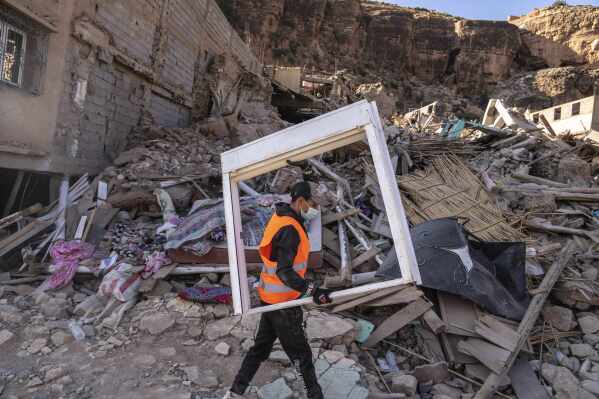 A volunteer helps salvage furniture from homes which were damaged by the earthquake, in the town of Imi N'tala, outside Marrakech, Morocco, Wednesday, Sept. 13, 2023. An aftershock rattled central Morocco on Wednesday, striking fear into rescue crews at work in High Atlas villages, digging people out from rubble that could slide. (AP Photo/Mosa'ab Elshamy)