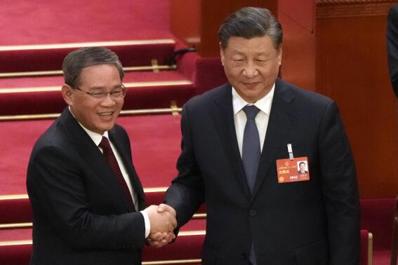 Newly elected Premier Li Qiang, left, shakes hands with Chinese President Xi Jinping during a session of China's National People's Congress (NPC) at the Great Hall of the People in Beijing, Saturday, March 11, 2023. (AP Photo/Mark Schiefelbein)