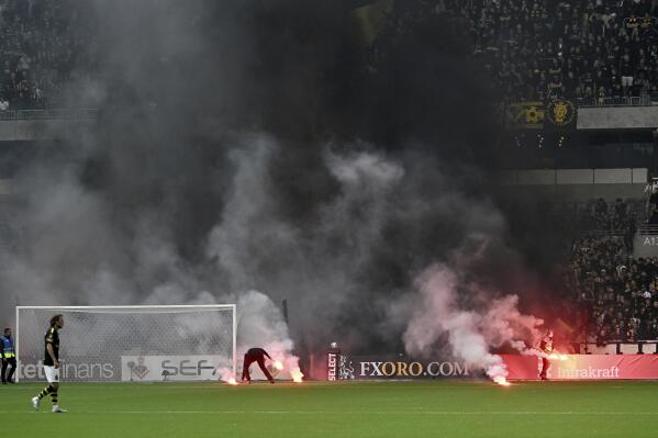 Flares are thrown on to the pitch by AIK supporters during the Allsvenskan soccer match between Djurgarden's IF and AIK at Tele2 Arena in Stockholm, Sweden, Sunday May 28, 2023. The Swedish government called an emergency meeting of the country’s soccer federation on Monday after crowd disorder during a match between Stockholm rivals AIK and Djurgardens that caused a one-hour delay. (Jonas Ekströmer/TT News Agency via AP)