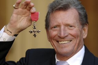FILE - In this March 7, 2007 file photo, actor Johnny Briggs poses for the media after collecting an MBE from Queen Elizabeth II at Buckingham Palace in London. British actor Johnny Briggs, best known for his role as businessman Mike Baldwin in the long-running TV soap opera “Coronation Street,” has died. He was 85. A statement from his family released Sunday, Feb. 28, 2021 said Briggs died peacefully after a long illness. (Fiona Hanson/PA via AP, file)