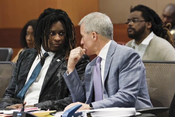 Atlanta rapper Young Thug, whose real name is Jeffery Williams, speaks with his attorney Brian Steel, right, during a motion hearing as the new Judge Paige Reese Whitaker presides after taking over the trial Tuesday, July 30, 2024, at the Fulton County courtroom in Atlanta. (Miguel Martinez/Atlanta Journal-Constitution via AP)