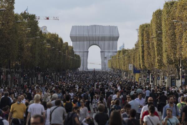 People walk along the Champs Elysees Avenue, Paris, during the "day without cars", with the Arc de Triomphe in the background, Sunday, Sept. 19, 2021. It is the sixth year the city has held a car free day in an attempt to reduce traffic and ease air pollution. (AP Photo/Lewis Joly)
