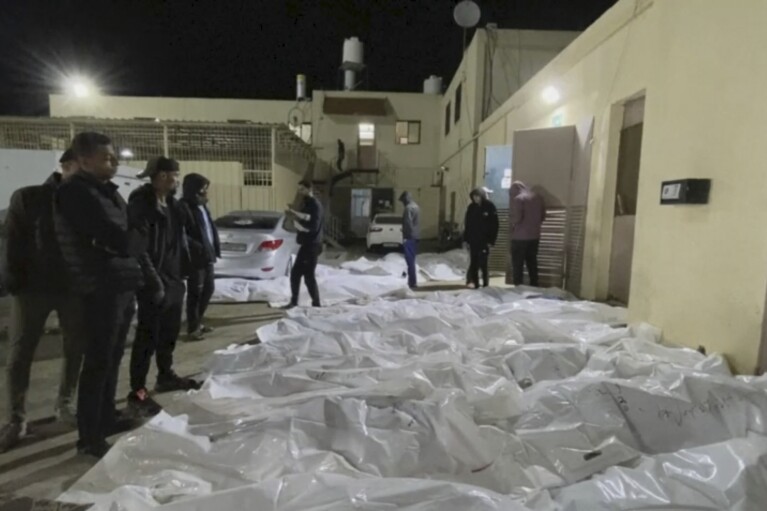 In this image from video, people look over some of the bodies which arrived at Al Aqsa hospital in Deir El Balah, Gaza on Sunday night, Dec. 24, 2023, after three strikes hit Central Gaza. (AP Photo)