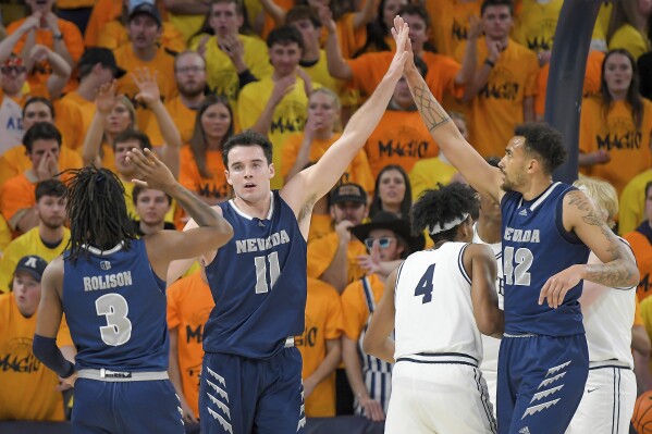 El delantero de Nevada Nick Davidson (11) celebra con el guardia Tyler Rolison (3) y el delantero KJ Hymes (42) después de hacer una canasta mientras recibía una falta contra Utah State durante la segunda mitad de un juego de baloncesto universitario de la NCAA el martes 6 de febrero de 2024. en Logan, Utah. (Eli Lucero/Herald Journal vía AP)