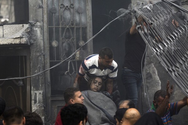 Palestinians evacuate a wounded woman from a destroyed house following Israeli airstrikes on Gaza City, Monday, Oct. 23, 2023. (AP Photo/Abed Khaled)