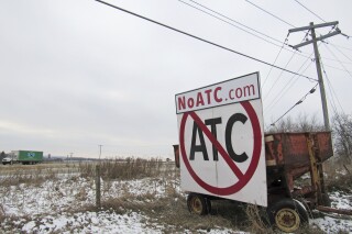 A grain wagon supports a sign along Highway 18-151 near Ridgeway, Wis. Signs against the proposed 345-kilovolt Cardinal-Hickory Creek transmission line are prolific along both routes proposed by American Transmission Co. of Pewaukee, ITC Midwest of Cedar Rapaids, Iowa, and Dairyland Power Cooperative of La Crosse. A coalition of conservation groups filed a last-minute federal lawsuit seeking to stop plans to build the high-voltage Hickory-Cardinal transmission line across a Mississippi River wildlife refuge. (Barry Adams/Wisconsin State Journal via AP, file)
