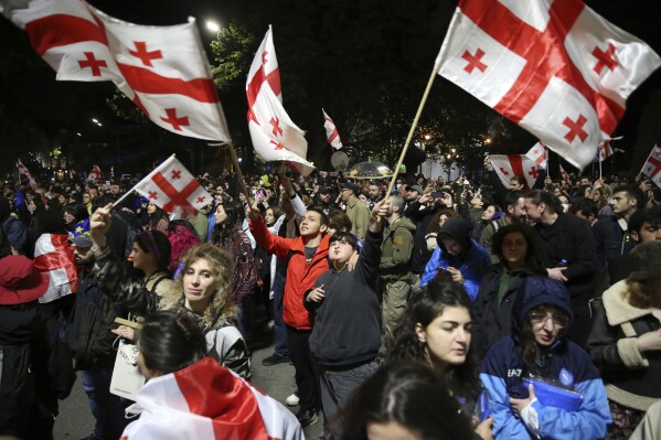 Demonstrators waving Georgian national flags gather in front of the Parliament building during an opposition protest against 