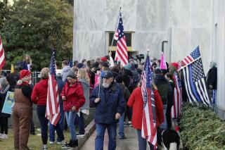 FILE - In this Dec. 21, 2020, file photo, pro-Trump and anti-mask demonstrators hold a rally outside the Oregon State Capitol as legislators meet for an emergency session in Salem, Ore. Prosecutors leveled two criminal charges Friday, April 30, 2021, against a Republican member of the Oregon House of Representatives who let far-right rioters into the state Capitol that day. Rep. Mike Nearman was charged with official misconduct in the first degree and criminal trespass in the second degree. (AP Photo/Andrew Selsky, File)