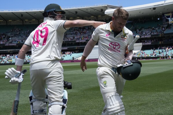 Australia's David Warner is patted on the back by teammate Australia's Steve Smith as Warner walks off the field after he lost his wicket to Pakistan on the fourth day of their cricket test match in Sydney, Saturday, Jan. 6, 2024. (AP Photo/Rick Rycroft)