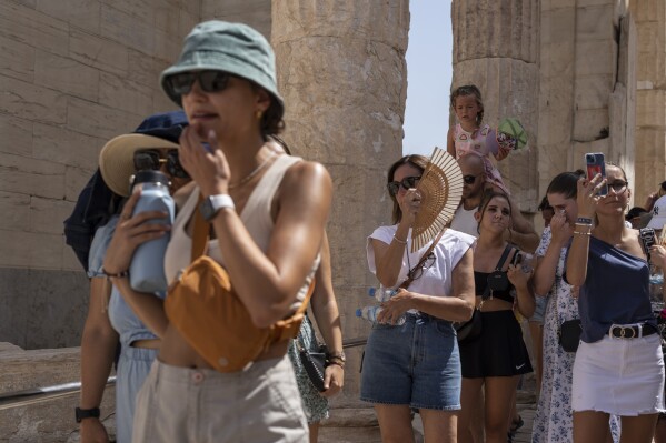 FILE - Tourists visit the ancient Acropolis hill during a heat wave in Athens, Greece, on July 21, 2023. Climate change is making heat waves crawl slower across the globe and last longer with higher temperatures over larger areas, a new study finds. (AP Photo/Petros Giannakouris, File)